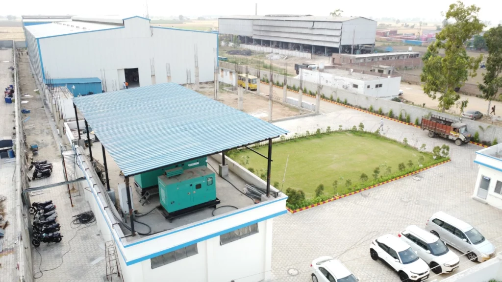 Scaffolding manufacturing plant with generator unit, office block, and industrial warehouse in background