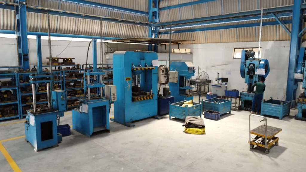 Scaffolding company workshop with blue machinery manufacturing scaffolding couplers, clamps, jacks and ring lock system parts